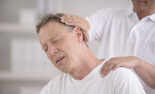 Ein Mann mit Osteochondrose des Halses an der Rezeption eines manuellen Massagegeräts